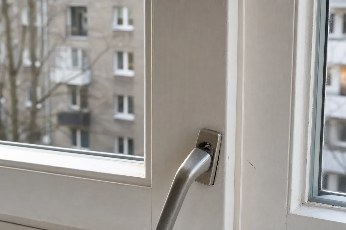 Fensterrahmen mit lockerem Griff und einem kleinen Kratzer rechts daneben.